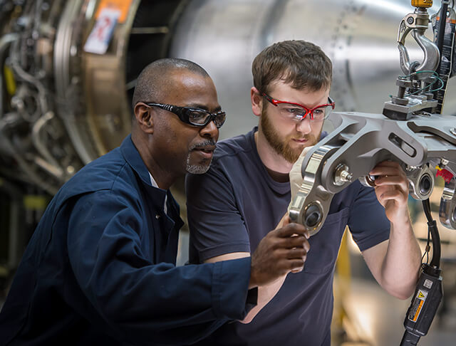 two male employees inspecting an aerospace engine part