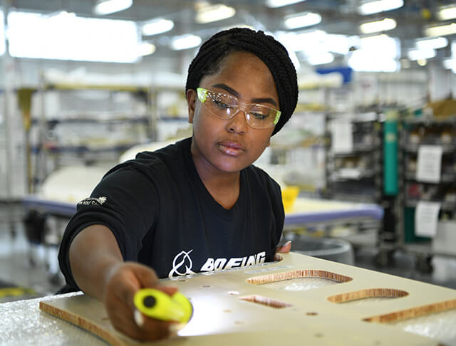 Female employee wearing safety goggles and working in a manufacturing facility