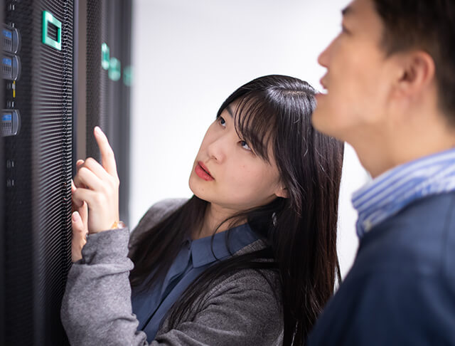 Korean male and Korean female employee inspecting a wall of servers and tech hardware