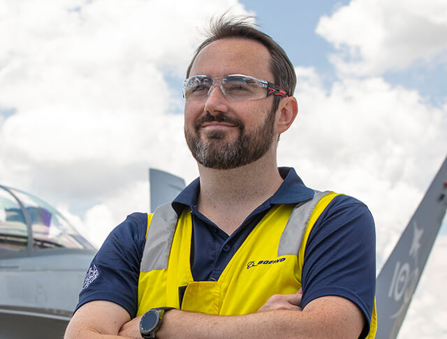 Jimmy M. wearing a reflective vest and standing in front of a jet plane