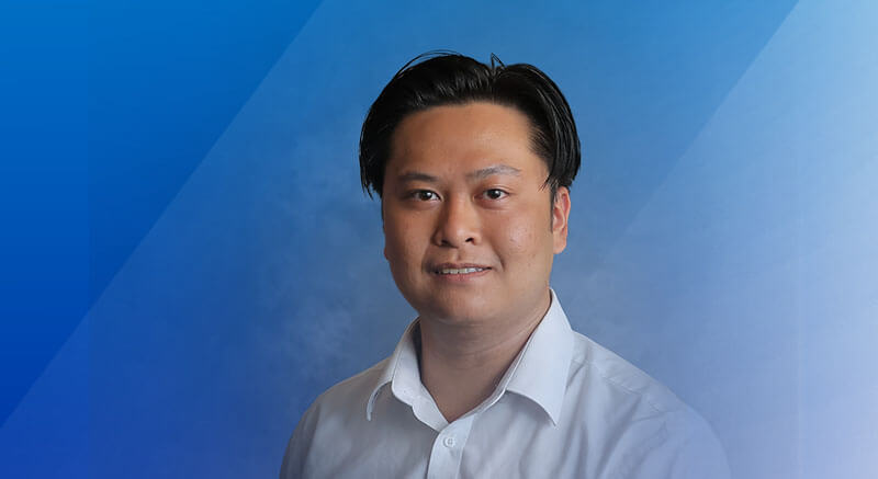 Photo headshot of Doan looking toward the camera with blue gradient background