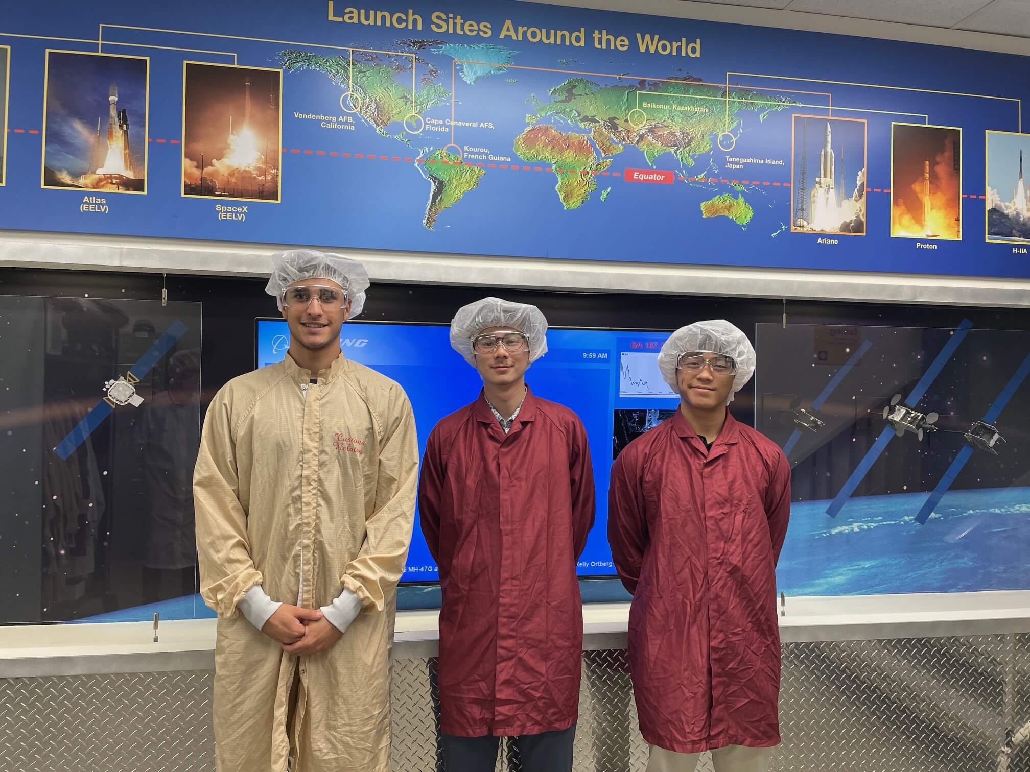 Adrian and two colleagues stand in front of the “Launch Sites Around the World” mural in the El Segundo Satellite Factory