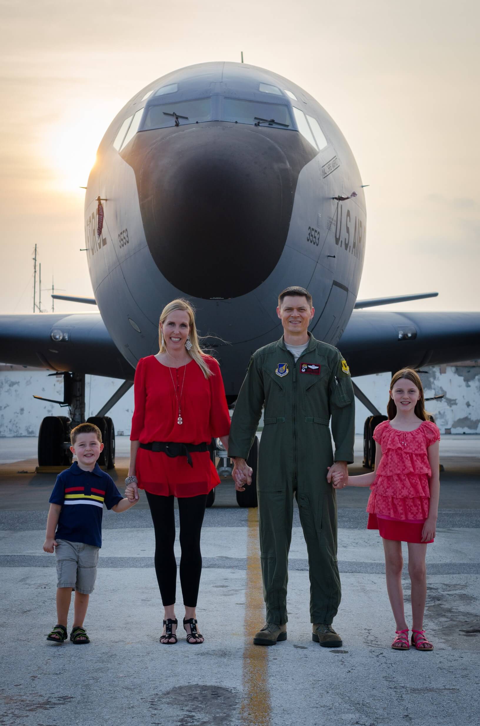 Family holding hands in front of a KC-135 aircraft