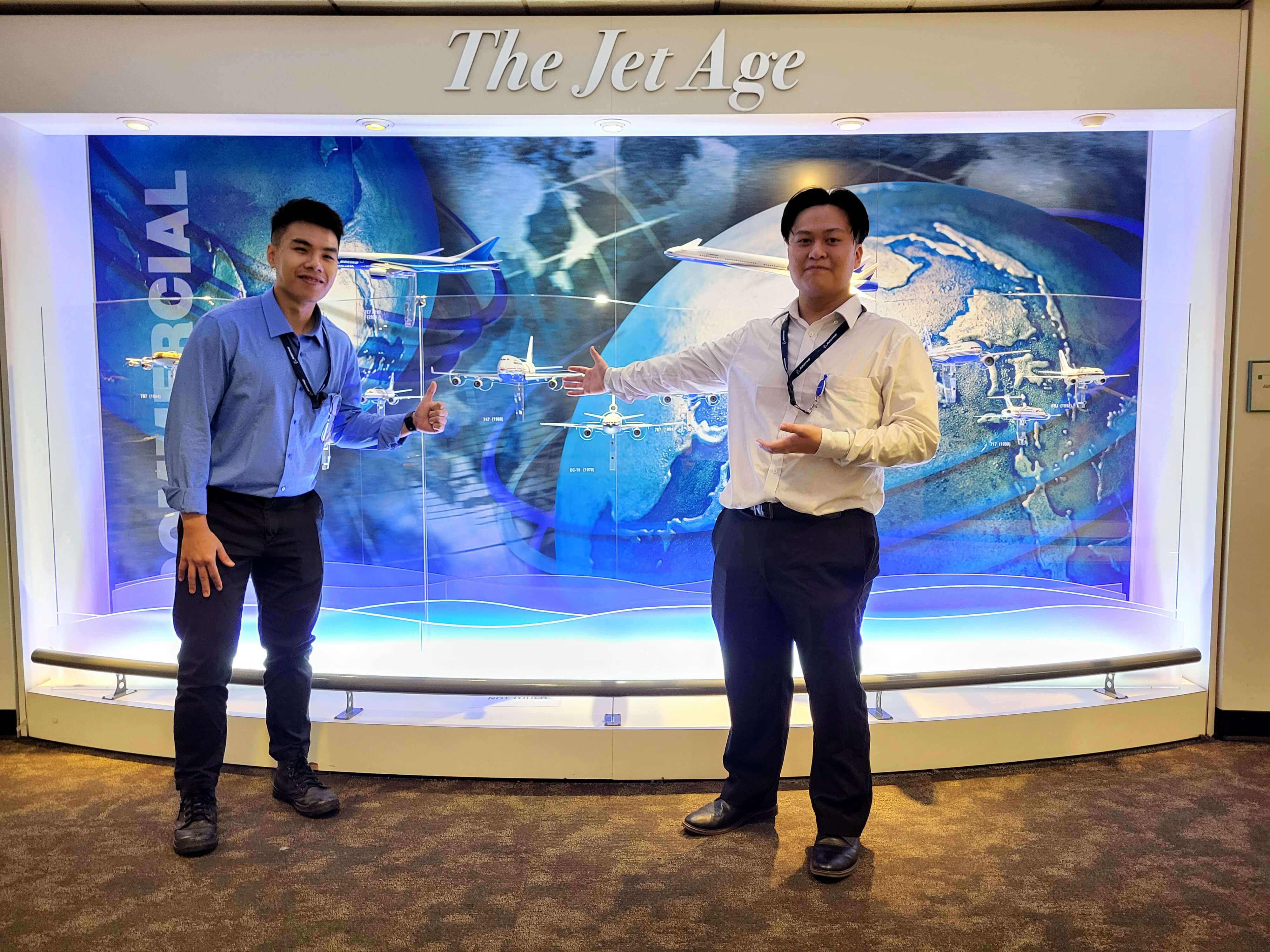 Alt text: Doan and a fellow intern stand  in front of a backlit mural labeled, “The Jet Age”