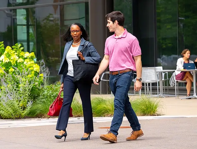 black female employee walking with a younger male employee outside a Boeing facility