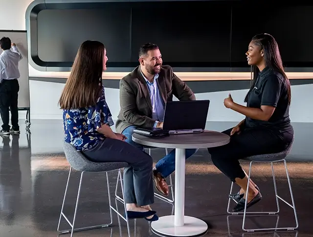 3 Boeing employees sitting at a table with a laptop and chatting