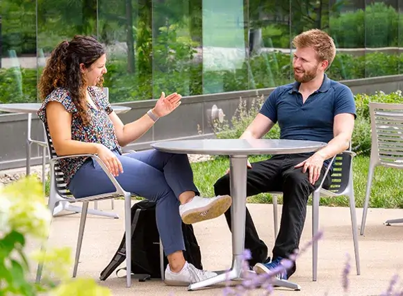 male and female employee sitting outside and chatting