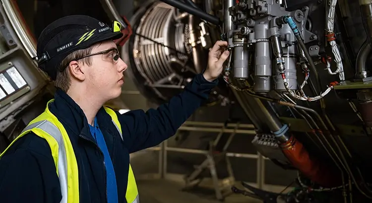 young male apprentice inspecting an aircraft engine