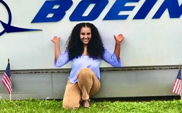 young female smiling in front of a building with the Boeing logo in view
