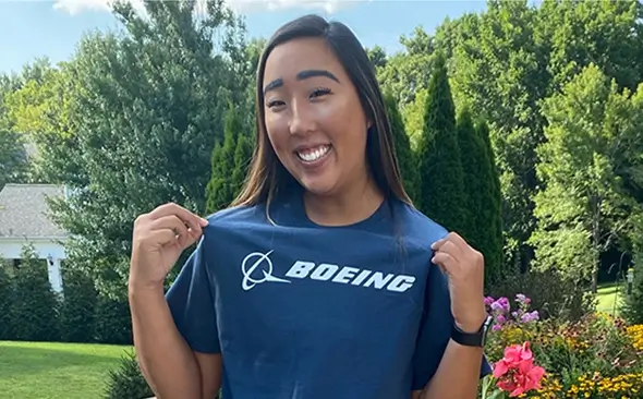 young Asian female in a backyard, smiling and showing off a Boeing t-shirt