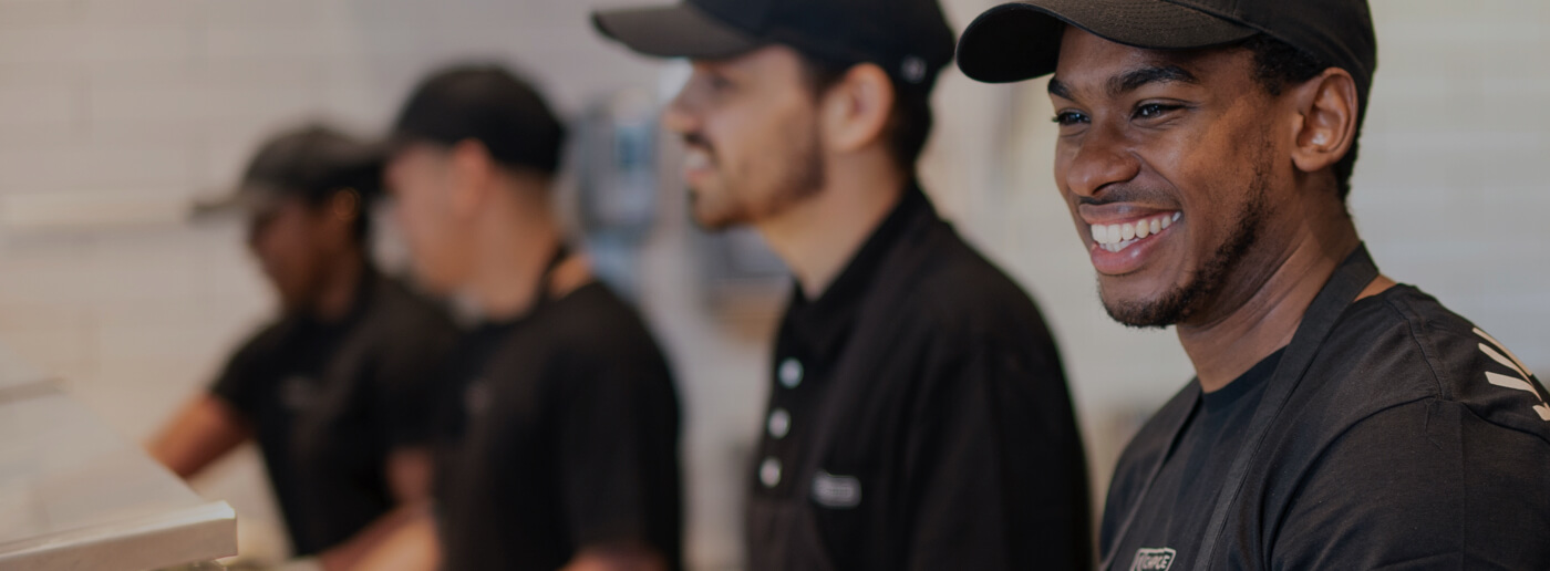 Crew members working happily together to serve bowls and burritos to restaurant guests.