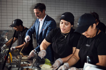 
El presidente y CEO de Chipotle, Brian Niccol, construye tazones y burritos con los miembros de Chipotle Crew en el restaurante.