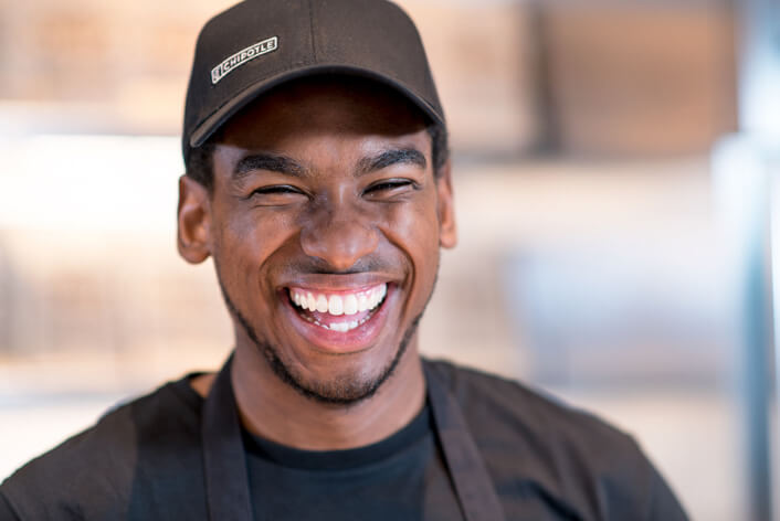 El miembro del equipo de Chipotle Restaurant Crew se ríe alegremente mientras sirve a los huéspedes en el restaurante.