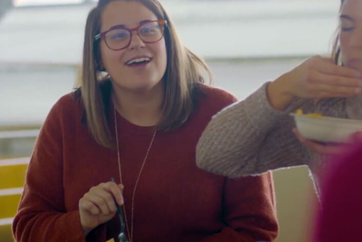 El personal de apoyo de Chipotle comparte una comida de Chipotle y se ríe en una conversación en el edificio de oficinas.