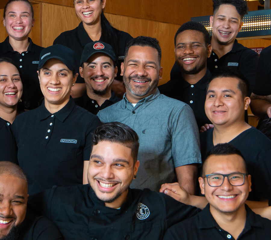 
El líder de campo de Chipotle, Jhonson, comparte su historia de liderazgo y es retratado con un feliz grupo de miembros de la tripulación en un restaurante.