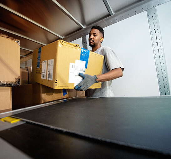 Banner: warehouse operative - One man woking and is holding a box next to a belt