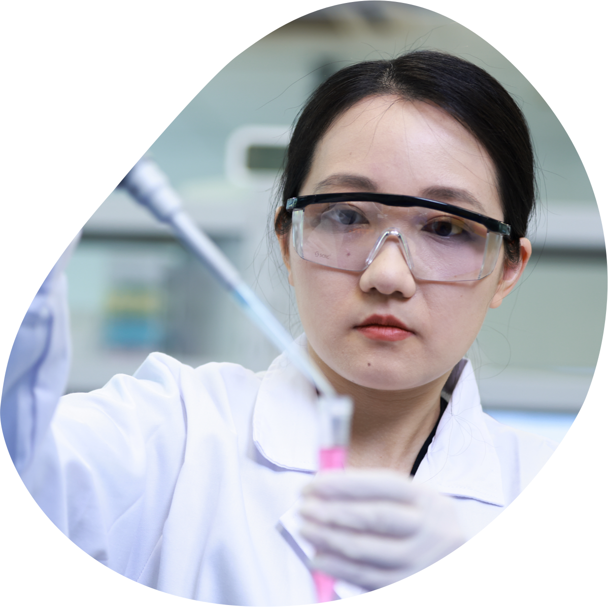 Woman in labcoat wearing safety goggles and holding a test tube