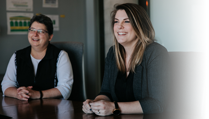 Two people laughing in a conference room