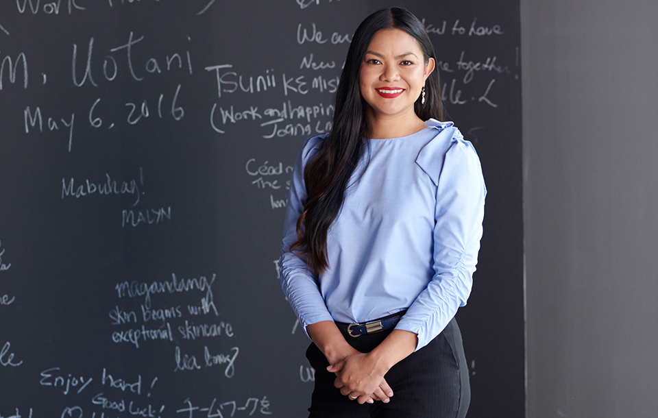 woman smiling in front of chalkboard