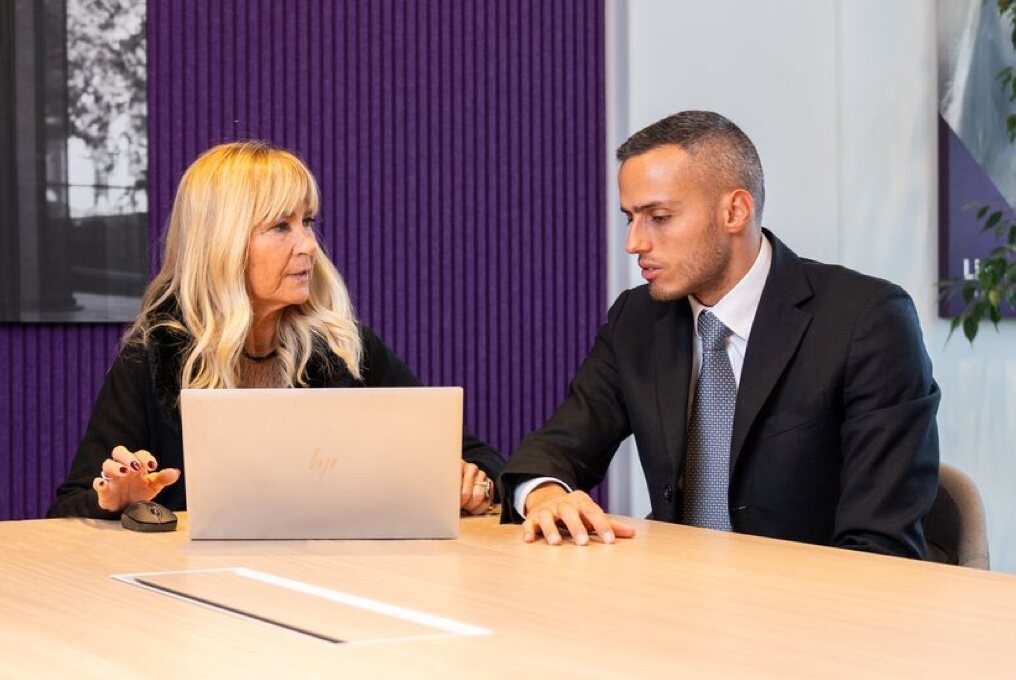 Een man en een vrouw gebruiken een laptop terwijl ze aan een tafel zitten.