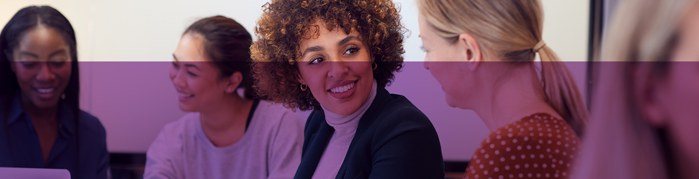 Gruppo diversificato di donne che sorridono durante una riunione.