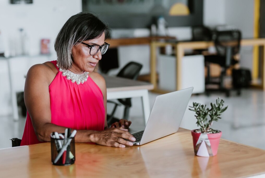 Een vrouw met een bril gebruikt een laptop voor werk.