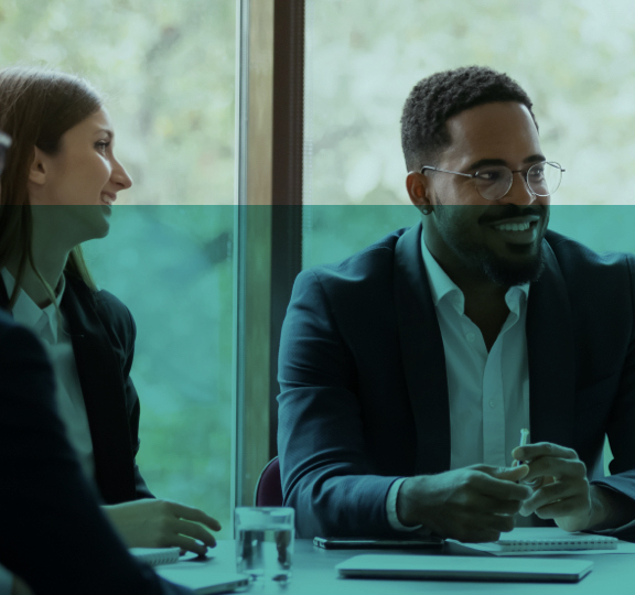 Groupe diversifié de professionnels en tenue de bureau assis autour d'une table de conférence, engagés dans une réunion.