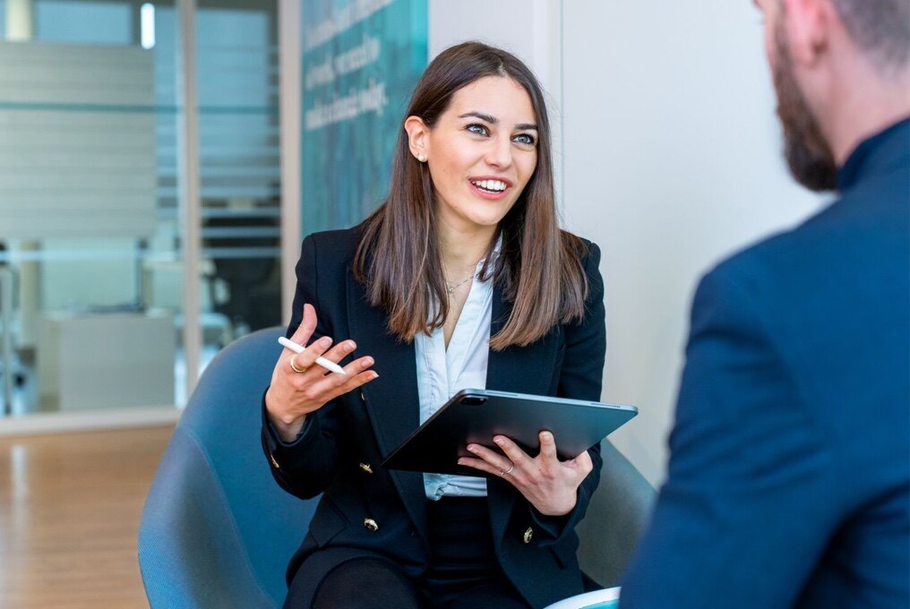 A professional woman in a suit having a discussion with a man.