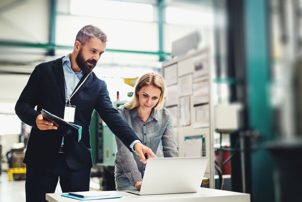 Un uomo e una donna in una fabbrica usando un laptop.