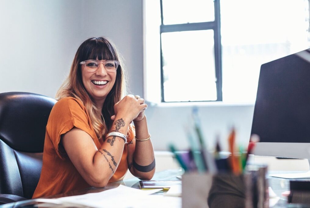 A woman smiling at her desk.