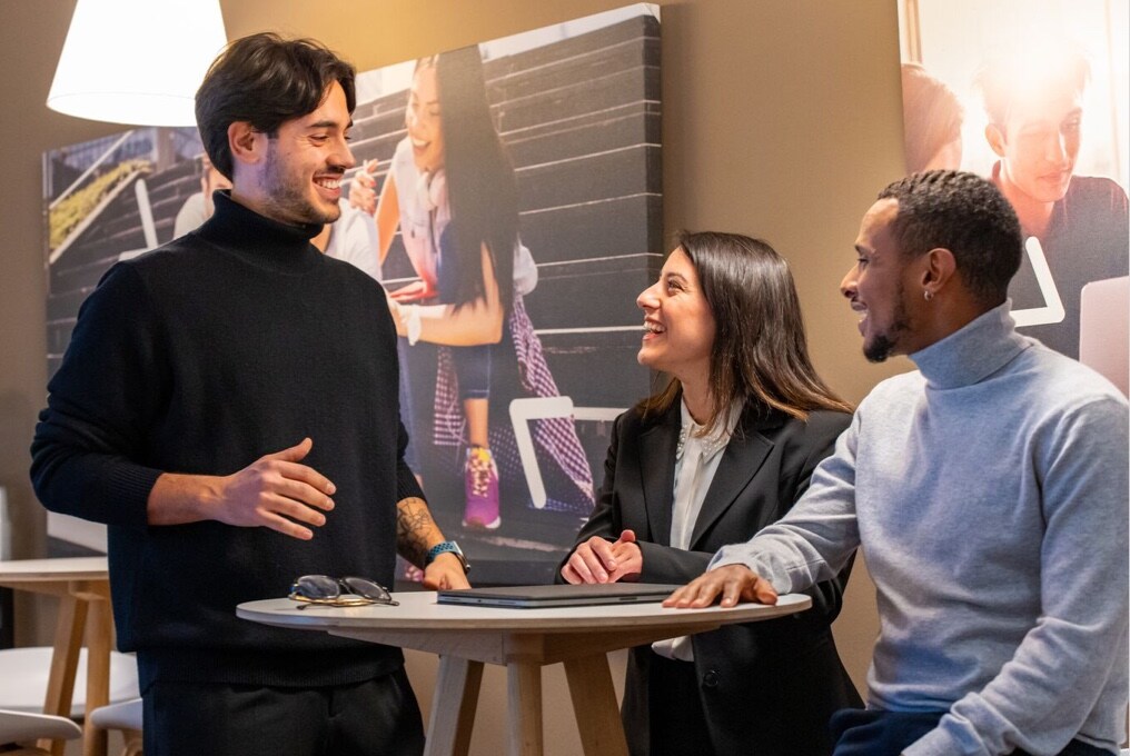 Three professionals discussing business matters in an office setting.