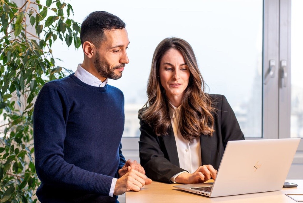 Twee collega's werken samen op een laptop.