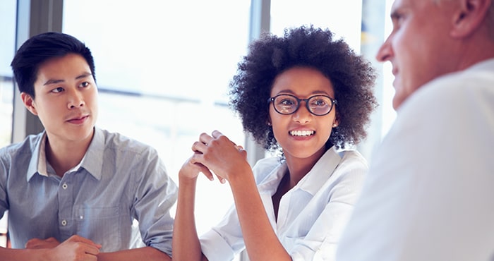 Three people talking while sitting around a white table