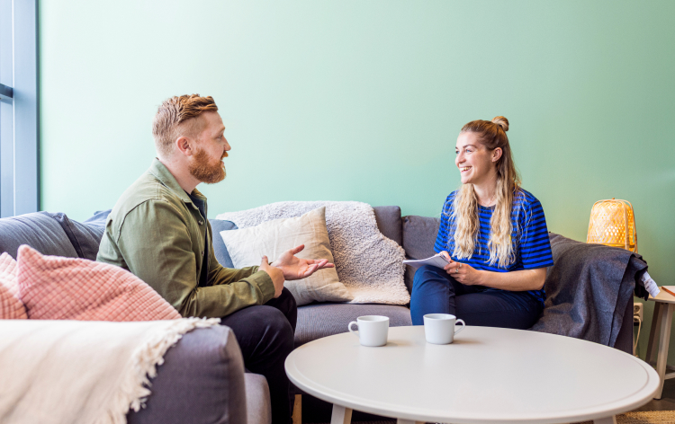 Two people talking while sat on a couch 1