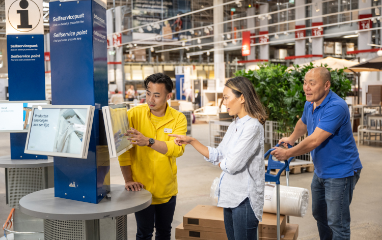 Ikea member of staff helping customers use touch screen