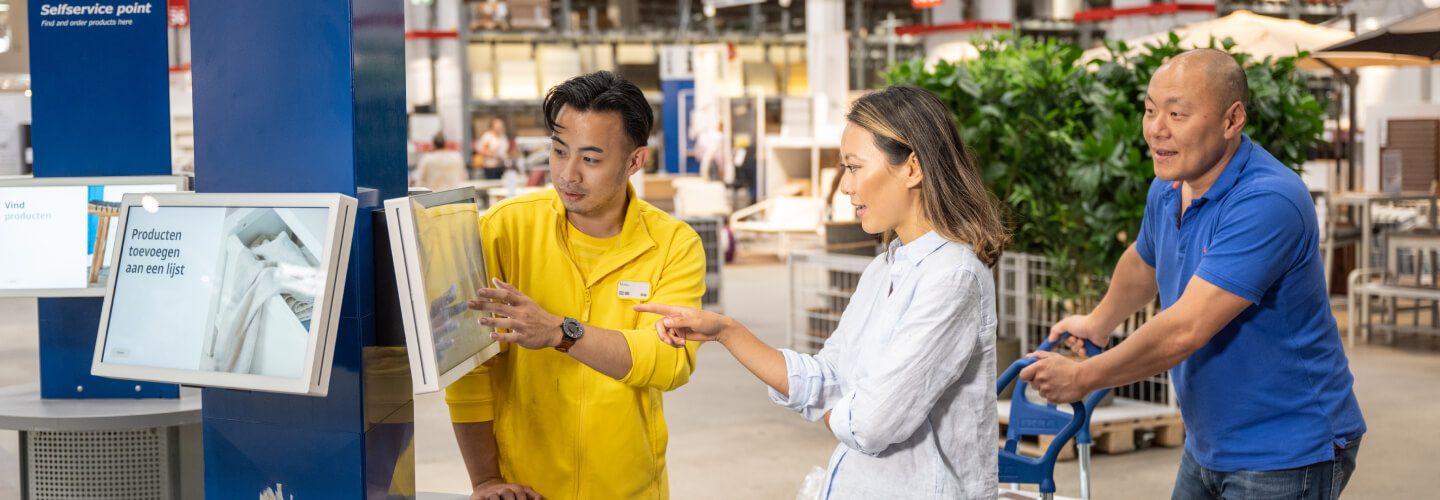 Ikea member of staff helping customers use touch screen