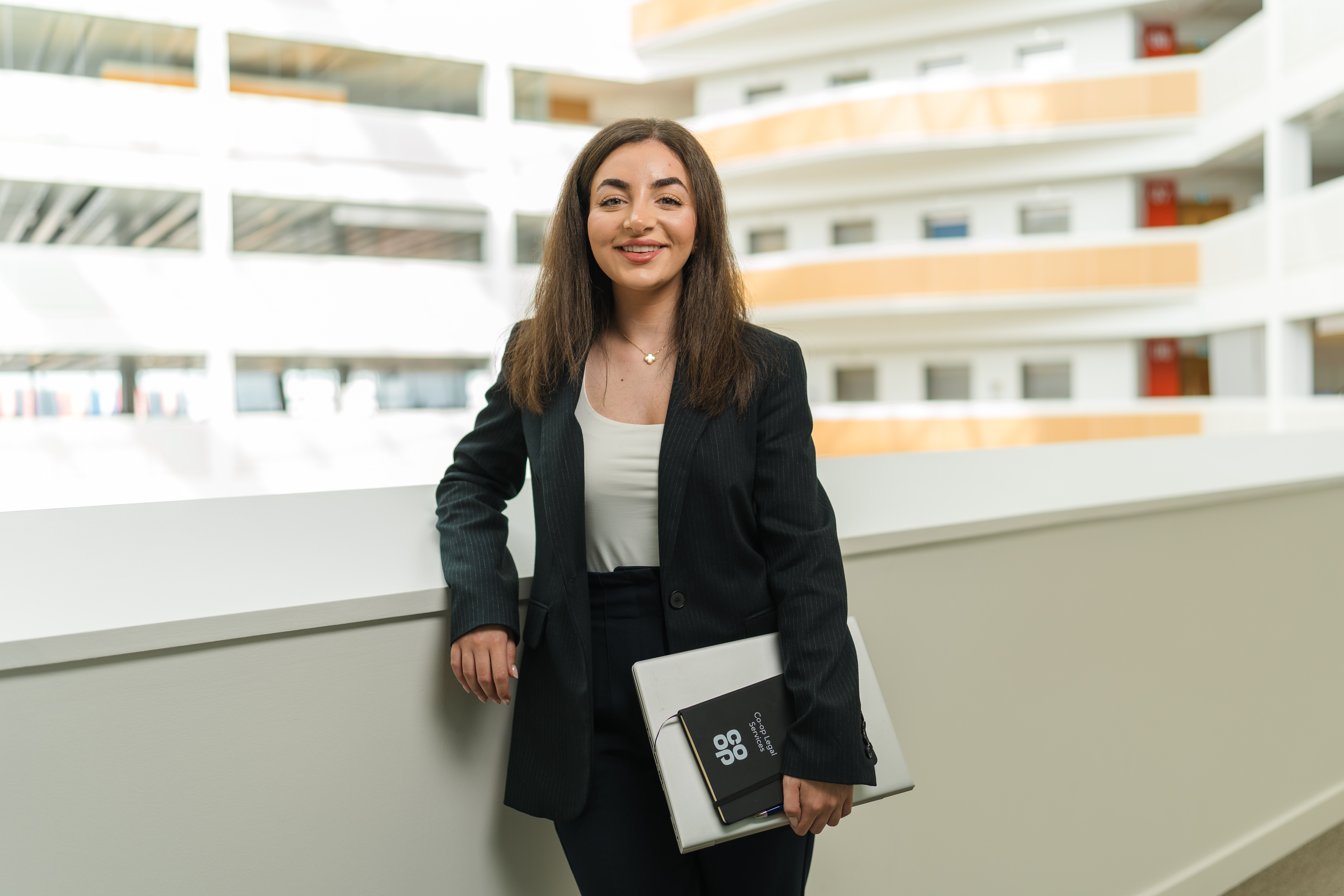Smiling female colleague leaning against the balcony inside the Co-op head office