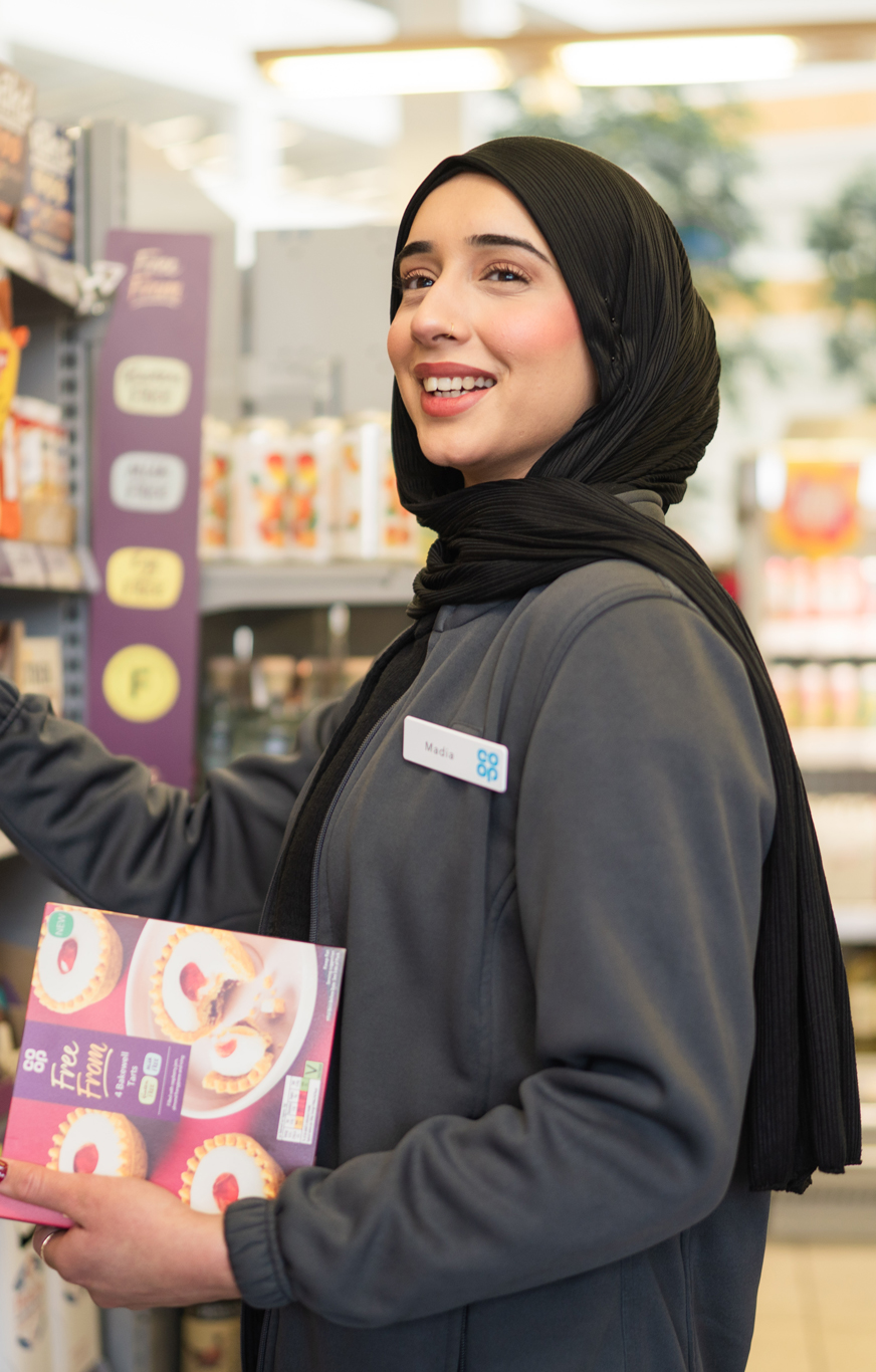 A retail professional with a headset and ID badge uses a handheld device