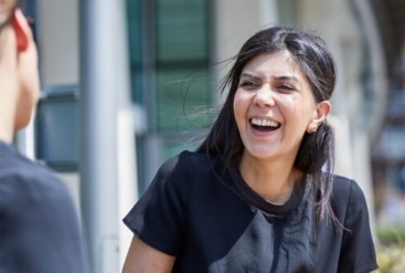 Two women talking and laughing outdoors on a sunny day