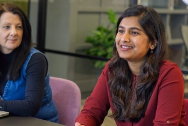 Two women smiling and talking in a modern office setting