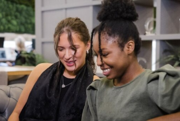 Two women smiling and looking at a laptop together