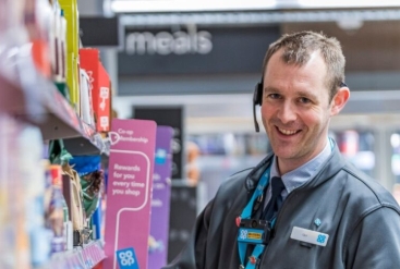 Smiling store employee with headset near product shelves
