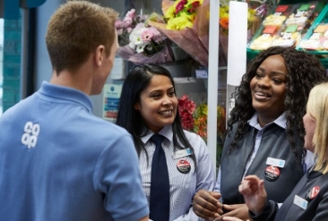Co-op employees smiling and chatting near flower section