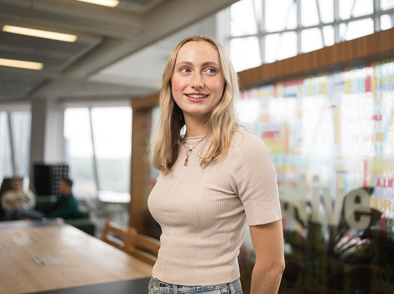 Individual in an office setting is standing and smiling