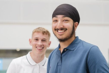 Two smiling men, one in a turban, posing indoors