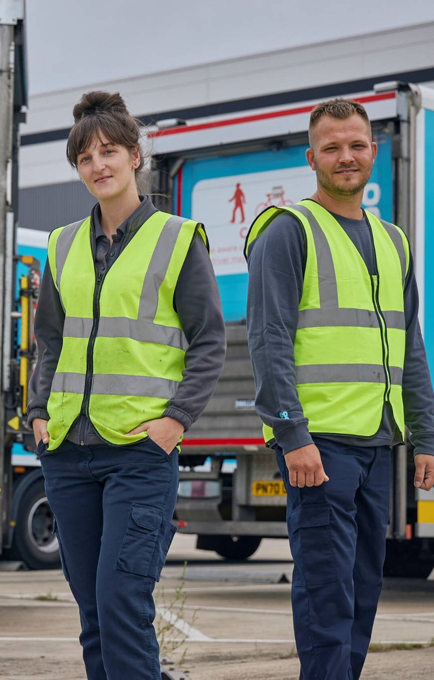 Team members in high-visibility vests standing in front of co-op branded trucks