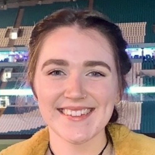 Smiling woman in a stadium with bright lights behind.