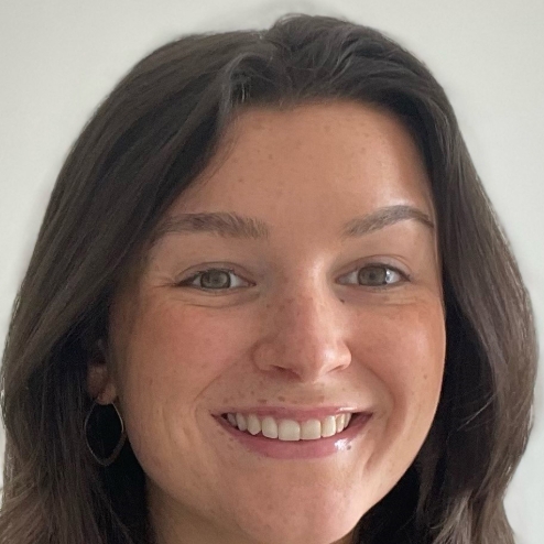 Smiling woman in white room, wearing hoop earrings.
