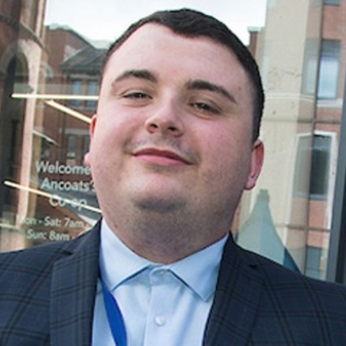 Man in suit standing outside Co-op store entrance.