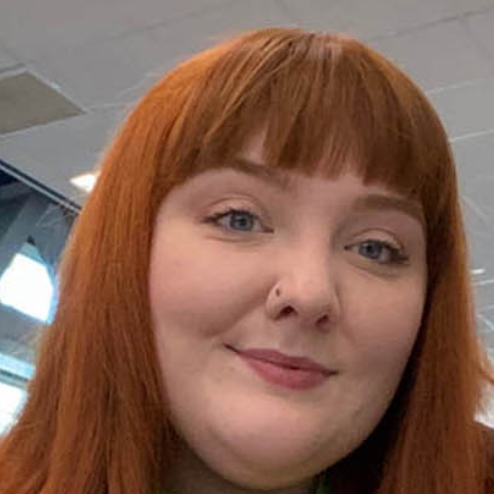 Woman with red hair smiling at her office desk.